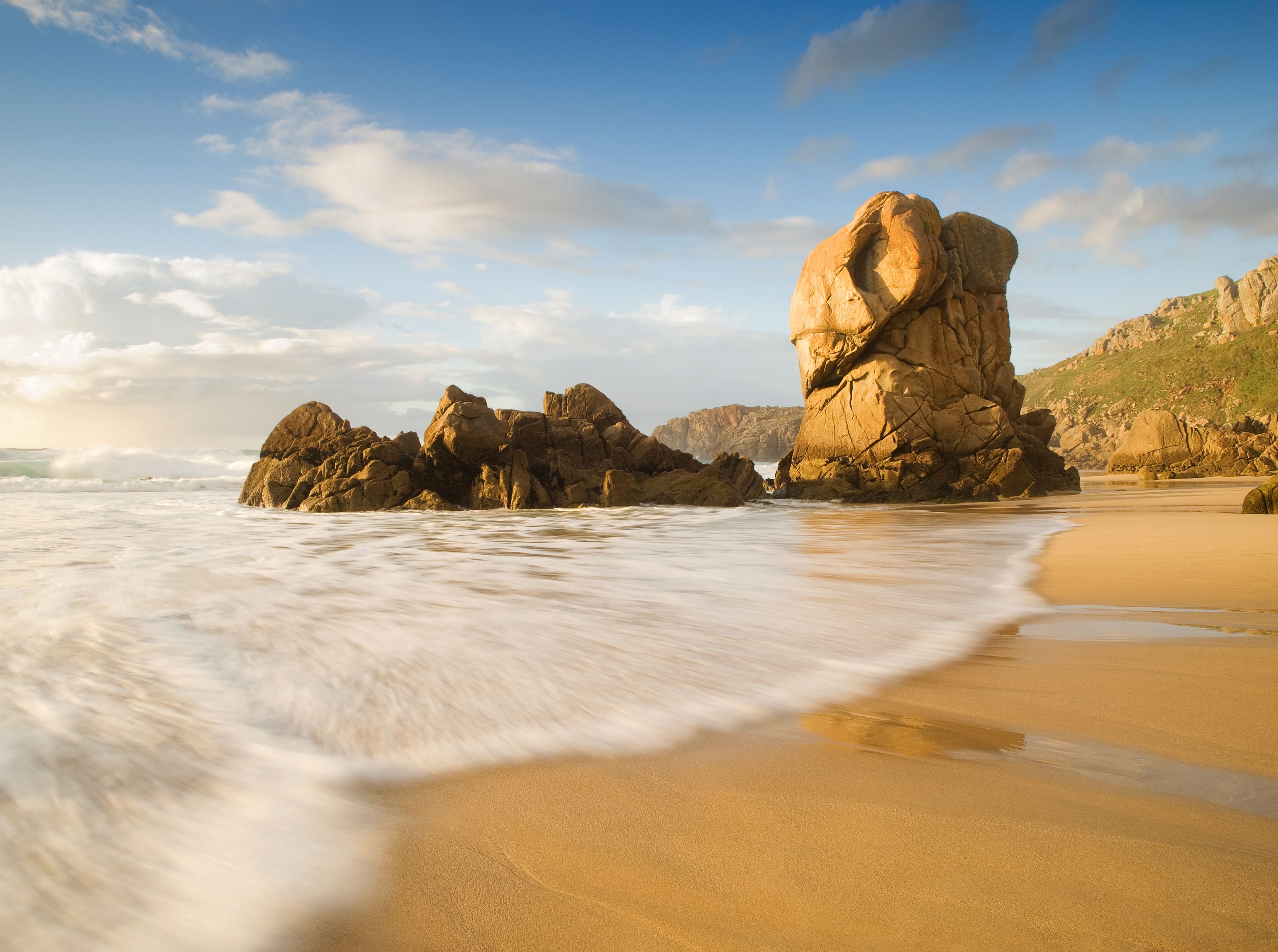 A beach with large rock formations and waves.