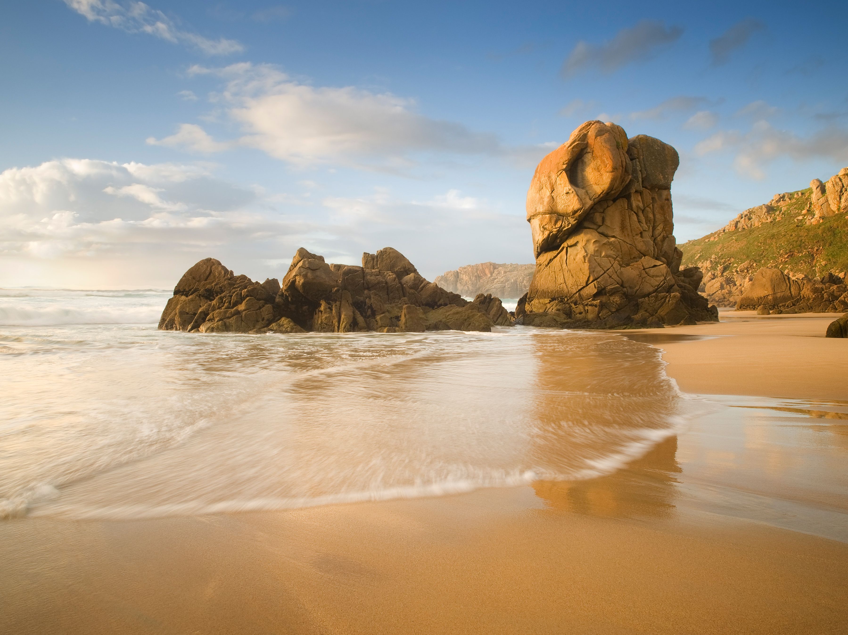 A beach with large rock formations and waves.