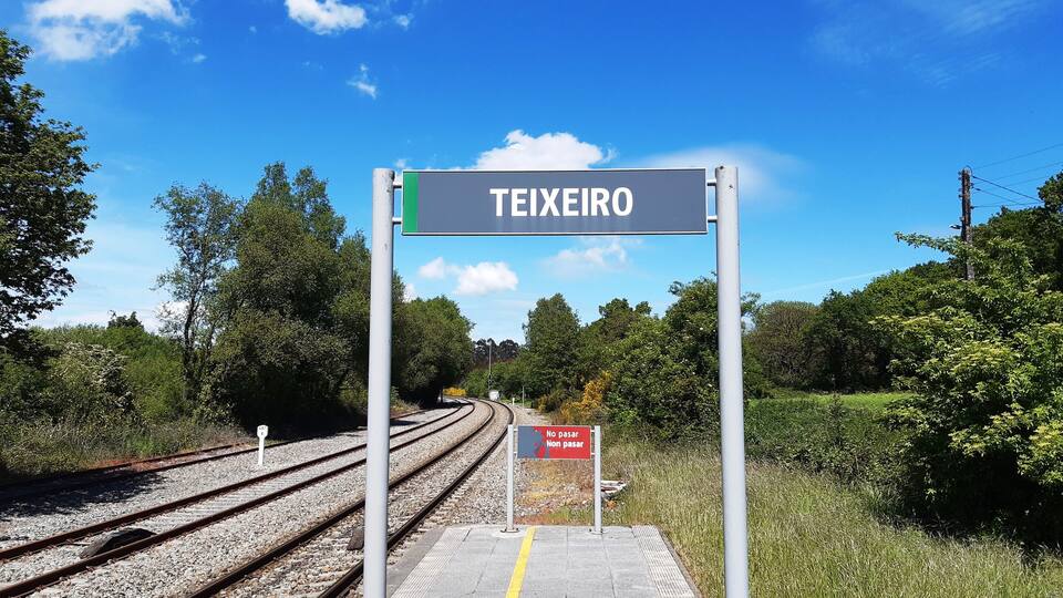 A railway station platform with a sign reading "TEIXEIRO" and a "NO PASAR" sign.