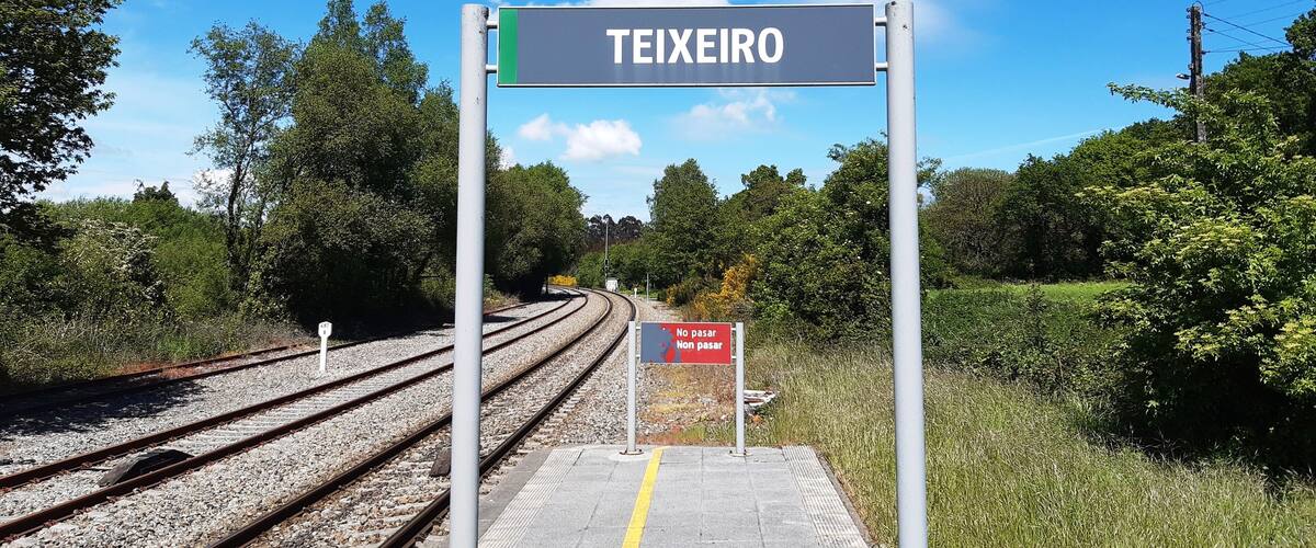A railway station platform with a sign reading "TEIXEIRO" and a "NO PASAR" sign.