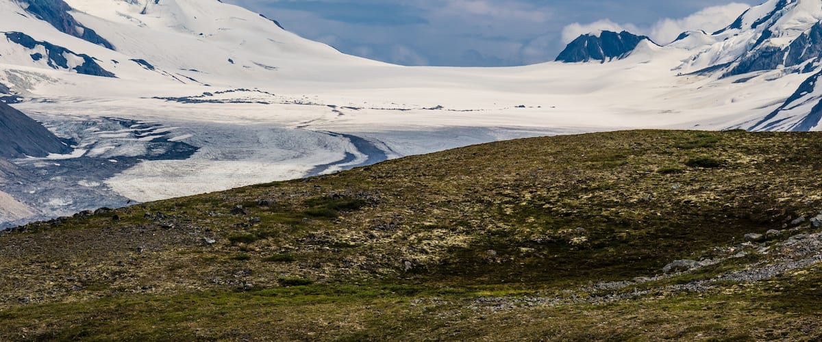 A glacier between mountains under a clear sky.