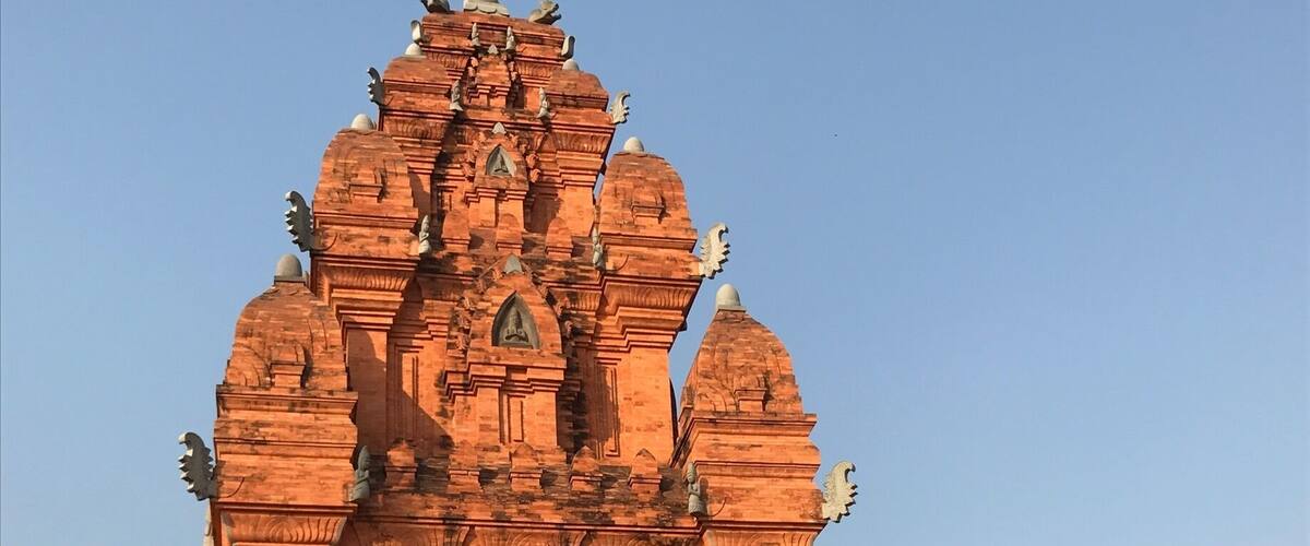 A large, red sandstone temple with intricate carvings and a central statue.
