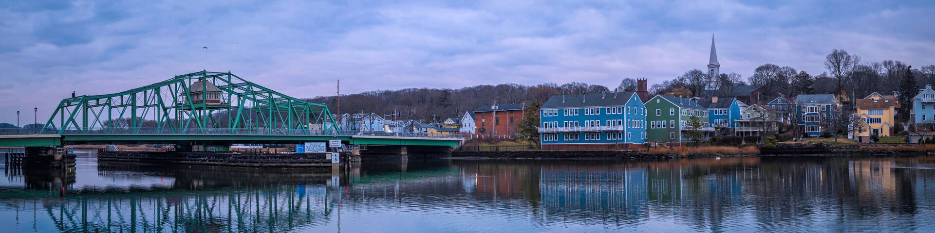 A New England winter landscape with the landmark Grand Avenue Swing Bridge and historic houses and church on the forest hill above the Quinipiac River in Fair Haven, New Haven County, Connecticut