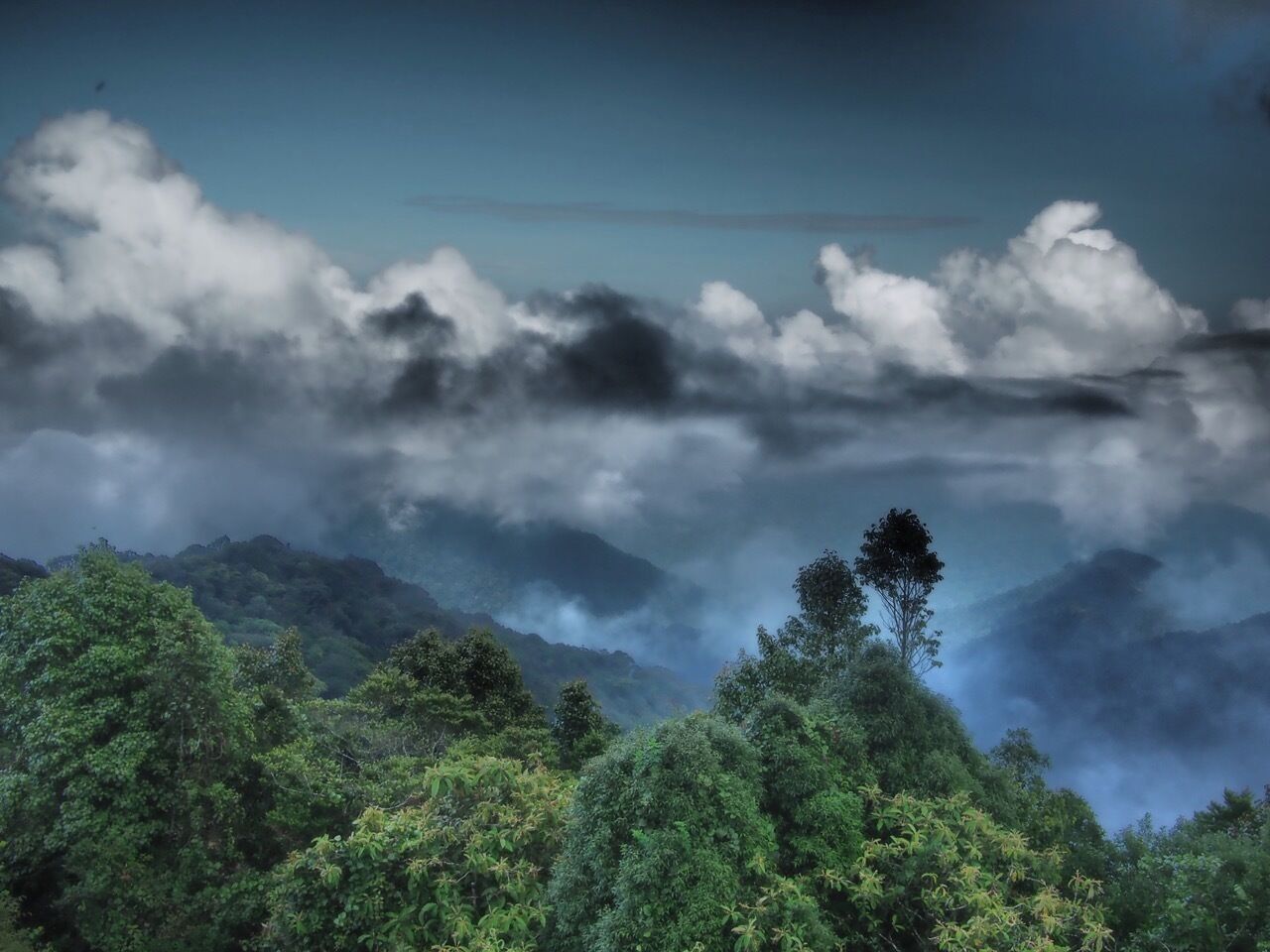 A mountainous landscape with dense green foliage and a clear sky.