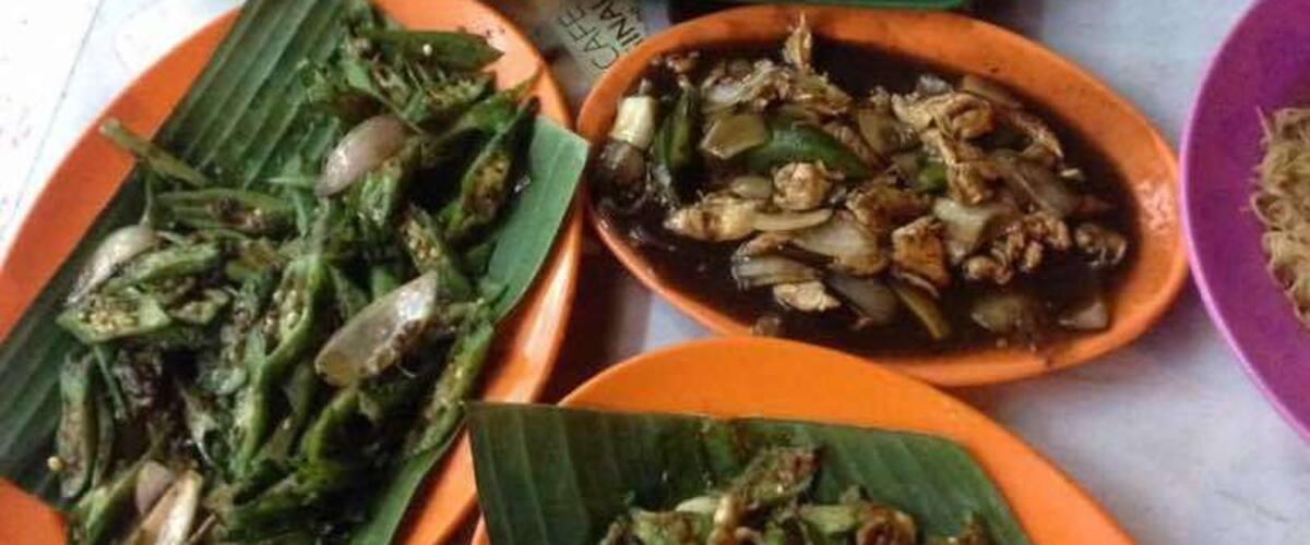 A variety of dishes served on banana leaves, including fried fish, stir-fried vegetables, and a plate of rice.