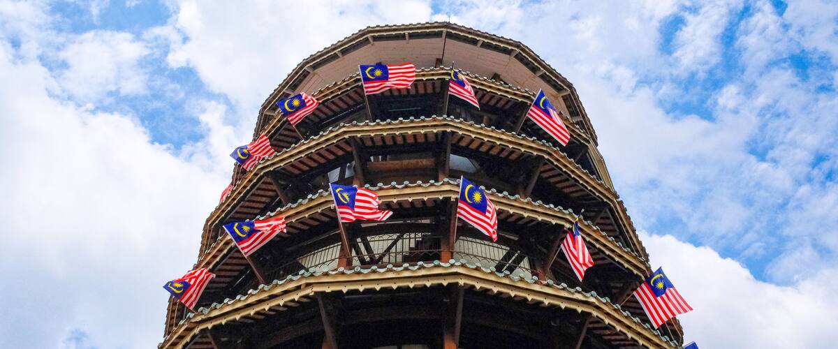 A multi-story building with multiple Malaysian flags.