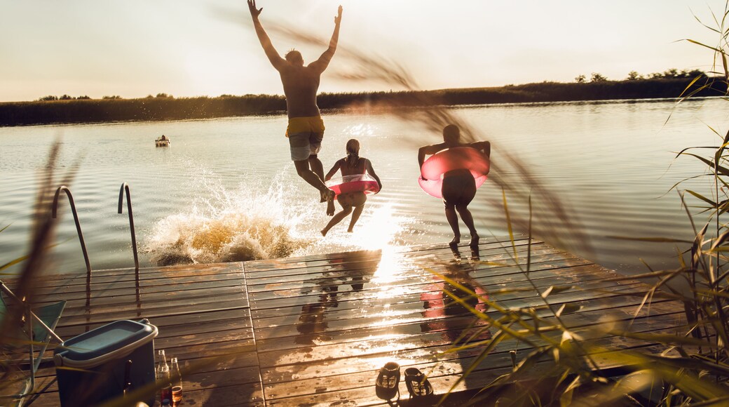 Friends having fun enjoying a summer day swimming and jumping at the lake.