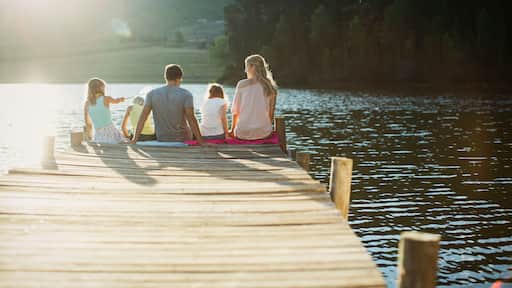 Family sitting at the edge of dock over lake