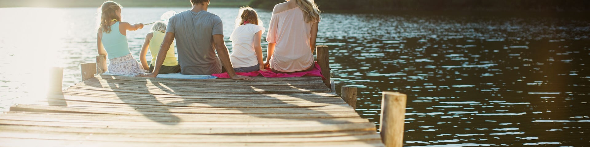 Family sitting at the edge of dock over lake