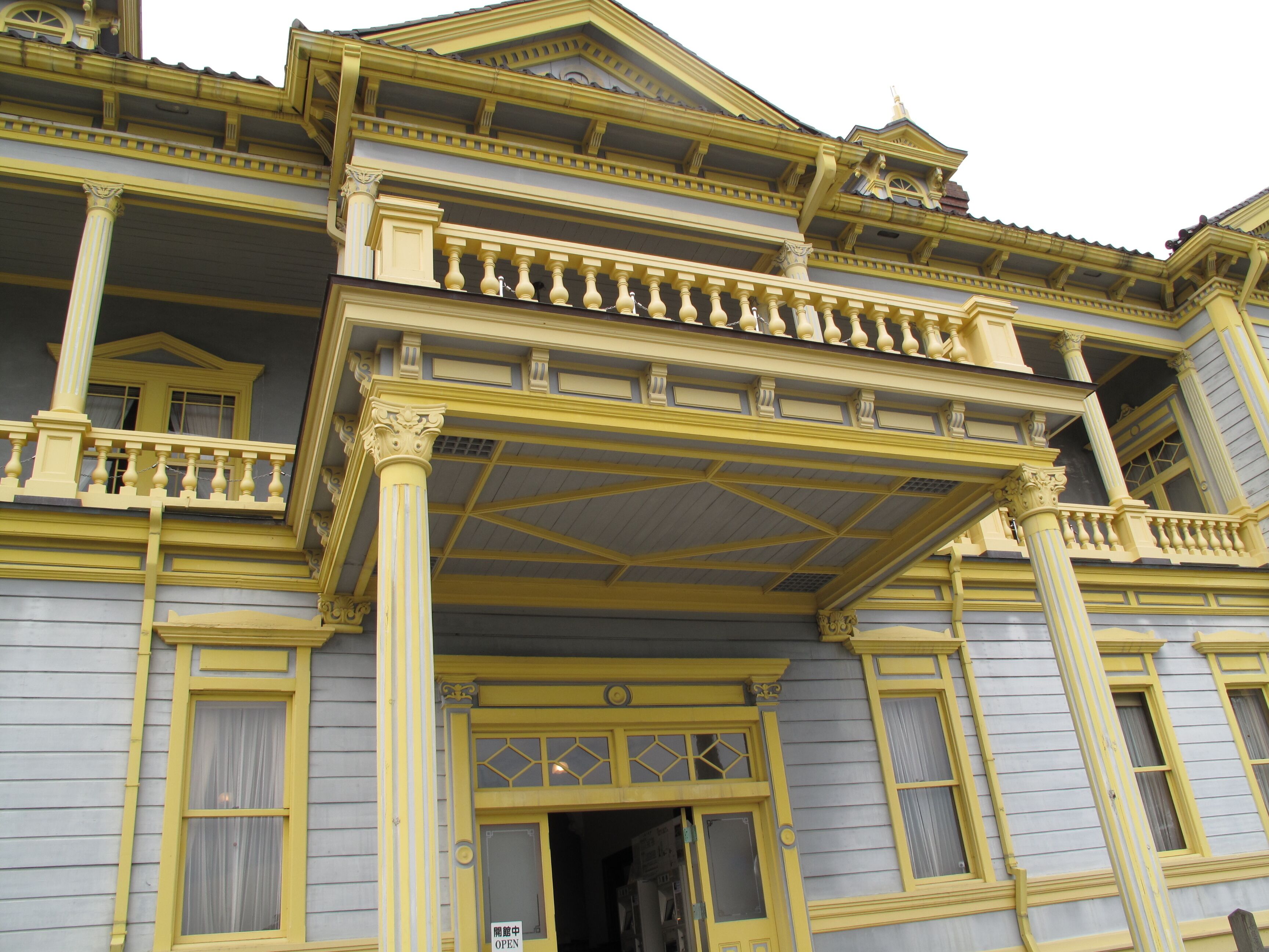 A yellow and gray building with ornate balconies and columns.