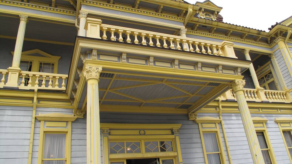 A yellow and gray building with ornate balconies and columns.