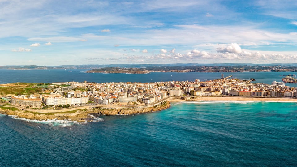 A coastal city with a prominent lighthouse, a marina, and a densely built urban area.