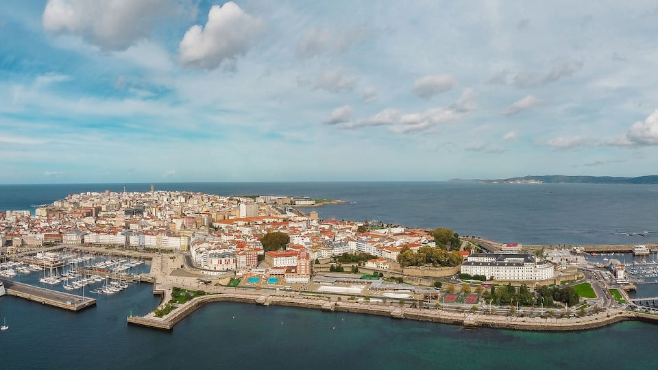 A coastal city with a marina, historic buildings, and a lighthouse.