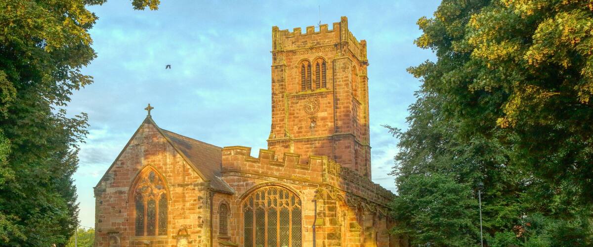 A historic church with a tall tower and a cemetery in the foreground.