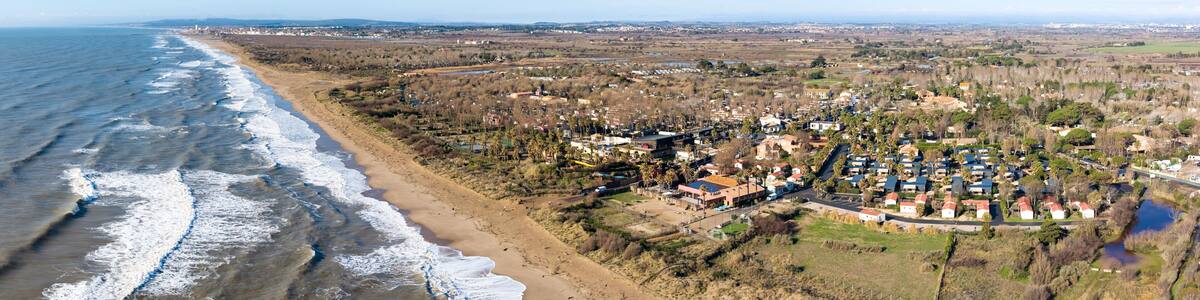 A coastal town with a beach, residential area, and distant hills.