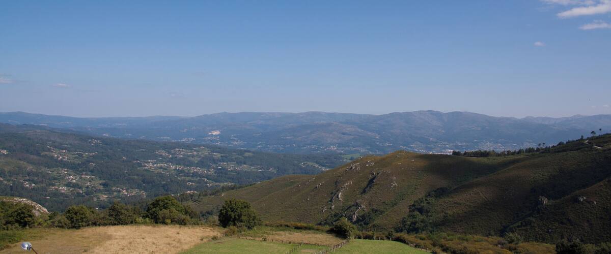 A panoramic view of rolling hills, a clear blue sky, and distant mountains.