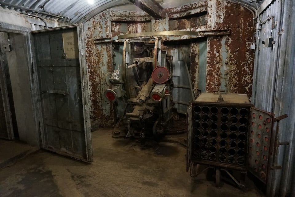 Een industriële omgeving met verroeste machines, een grote deur en een metalen rek met ronde gaten.