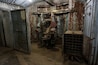An industrial setting with rusted machinery, a large door, and a metal rack with circular holes.