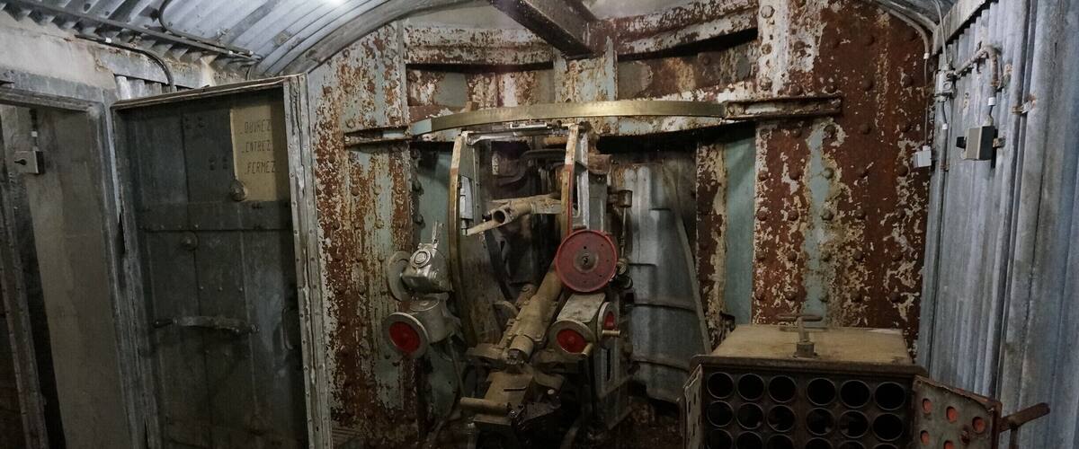 An industrial setting with rusted machinery, a large door, and a metal rack with circular holes.