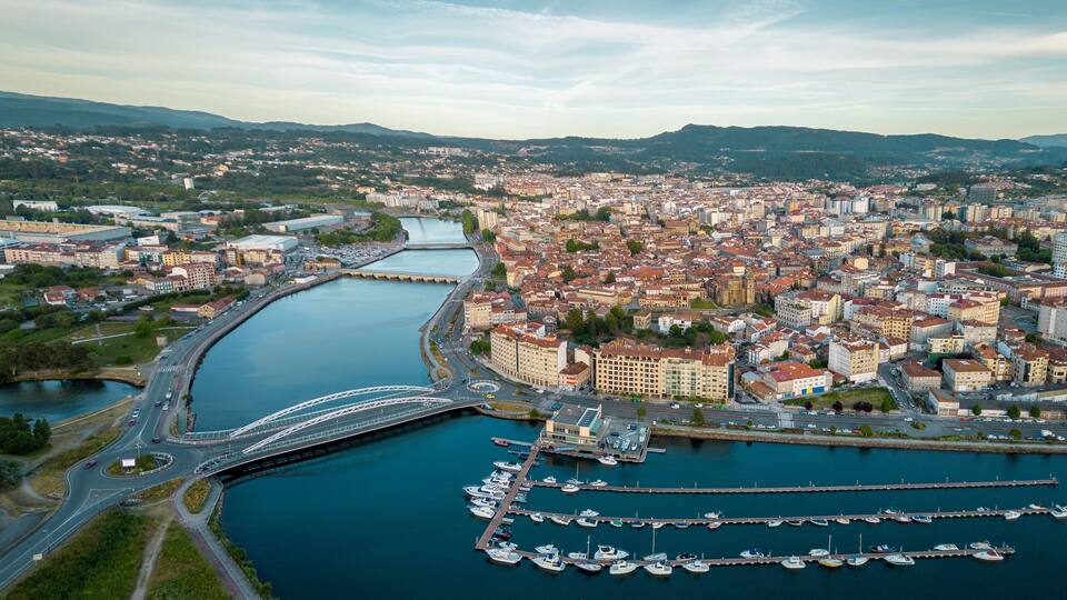 Un paisaje urbano con un río, un puente y un puerto deportivo con barcos.