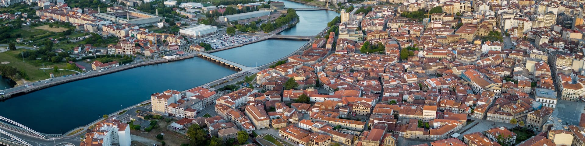 An aerial view of a city with a river, bridges, and a mountainous backdrop.
