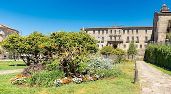A historic building with a stone facade, a cobblestone pathway, and a well-maintained garden with various flowers and trees.