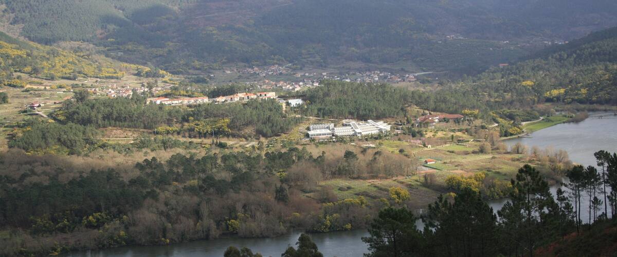 A river winding through a valley with a town and forested hills in the background.
