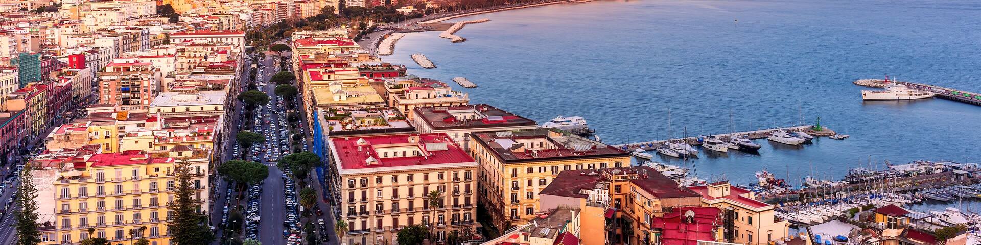 amazing Naples landscape of Vomero hill with beautiful streets and buildings of Napoli city, blue sea gulf and volcano Vesuveus with sunset of sunrise cloudy sky on background