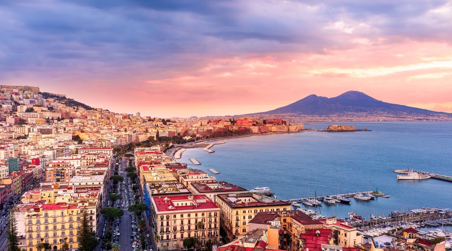 amazing Naples landscape of Vomero hill with beautiful streets and buildings of Napoli city, blue sea gulf and volcano Vesuveus with sunset of sunrise cloudy sky on background