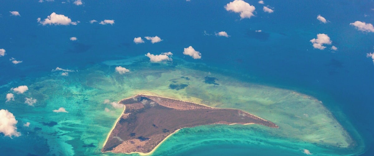 An aerial view of a turquoise island surrounded by clear blue waters.
