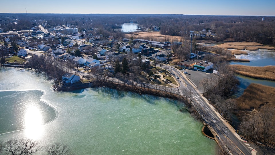 An aerial view of a town with a frozen river, houses, and a bridge.