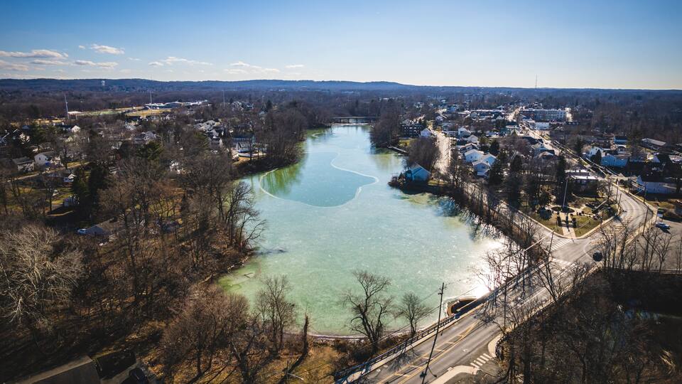 A river winding through a town with houses and a bridge.