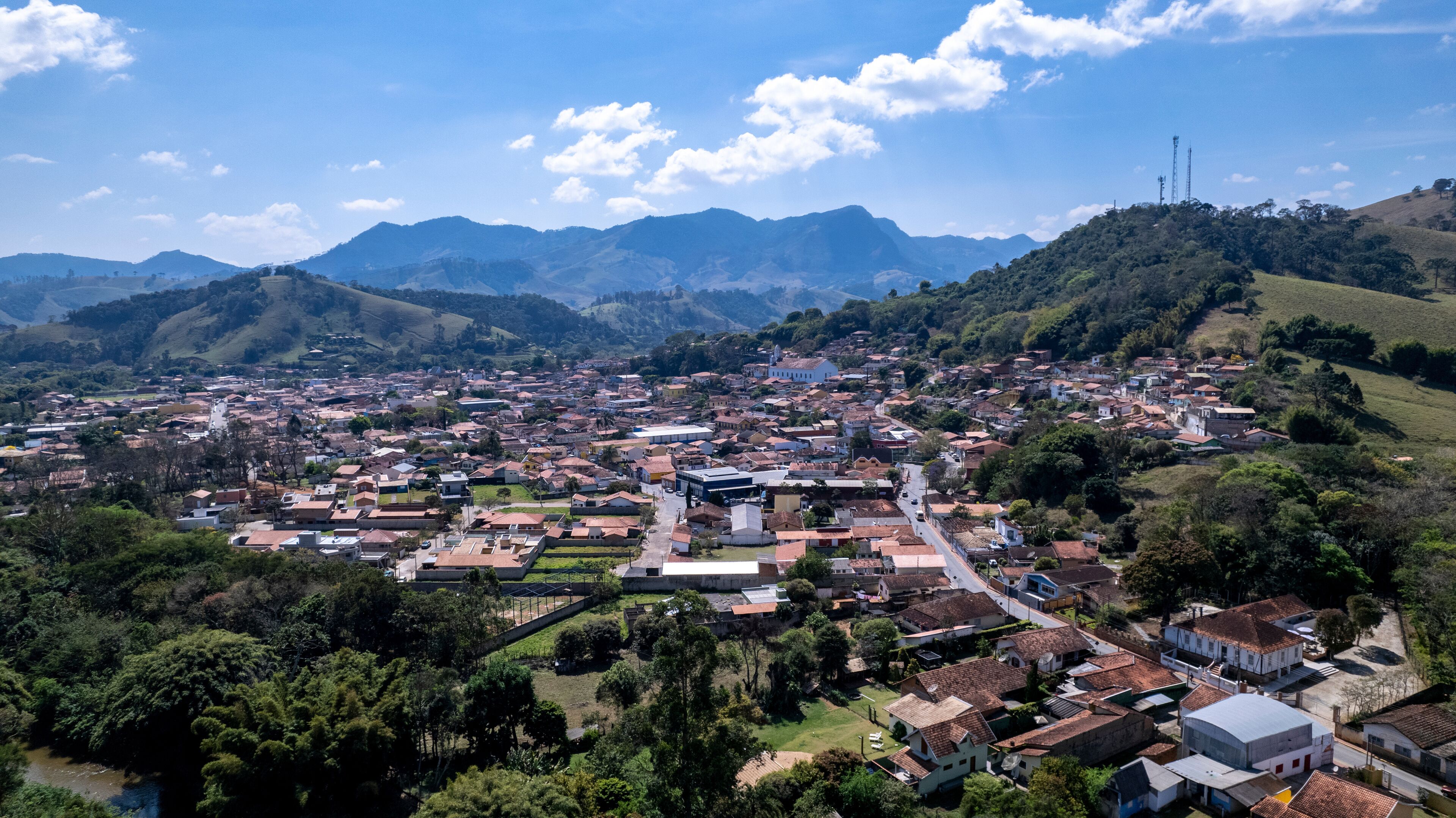 A town with a river, surrounded by mountains and greenery.