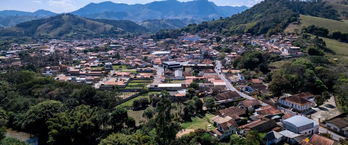 A town with a river, surrounded by mountains and greenery.