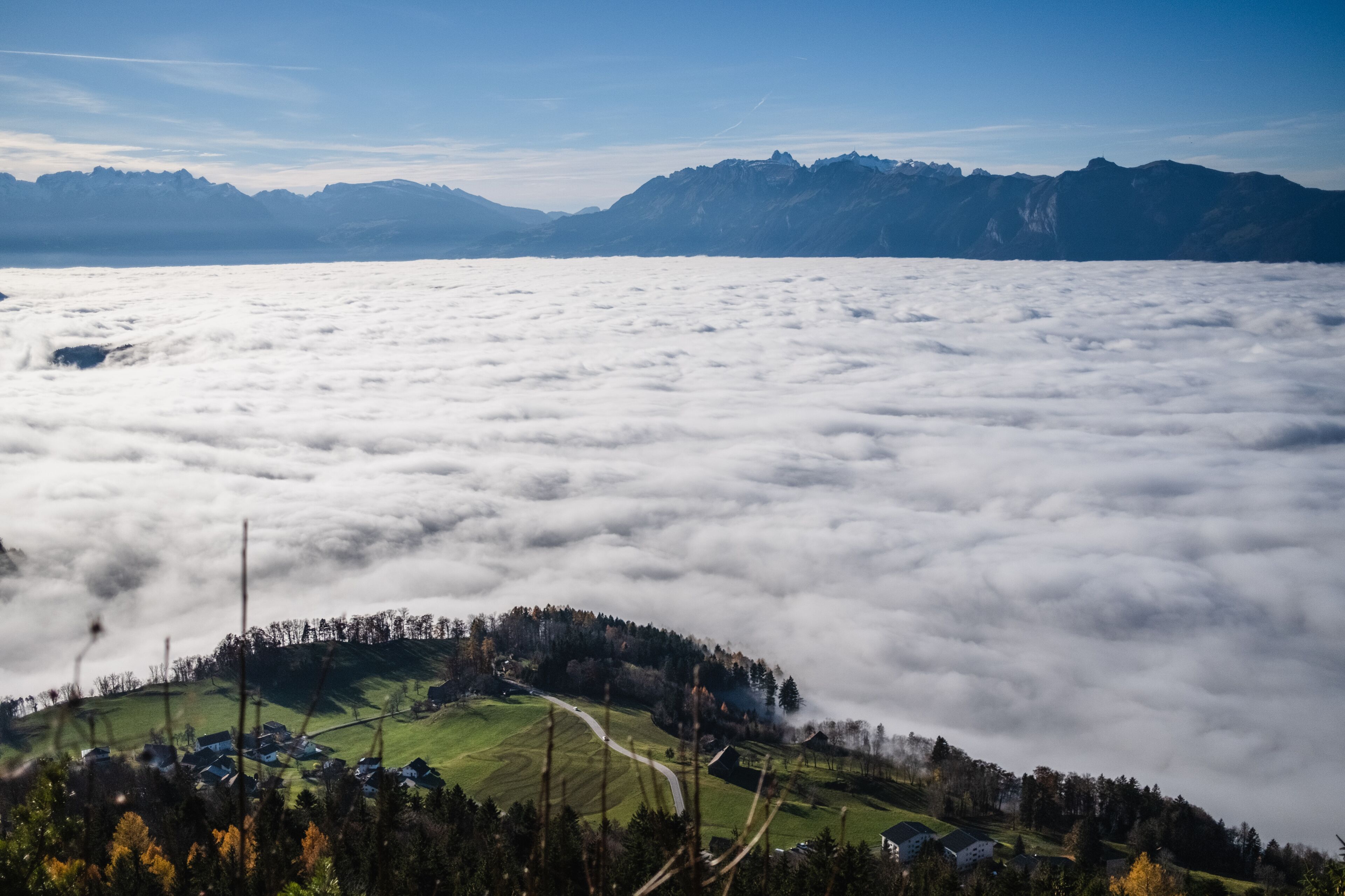 A village nestled among clouds with mountains in the background.