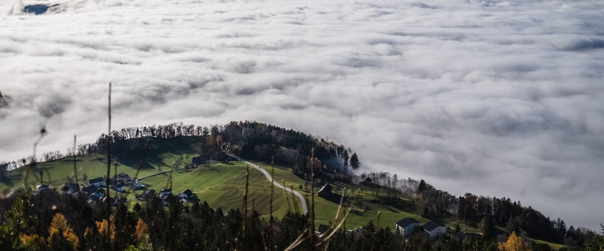 A village nestled among clouds with mountains in the background.