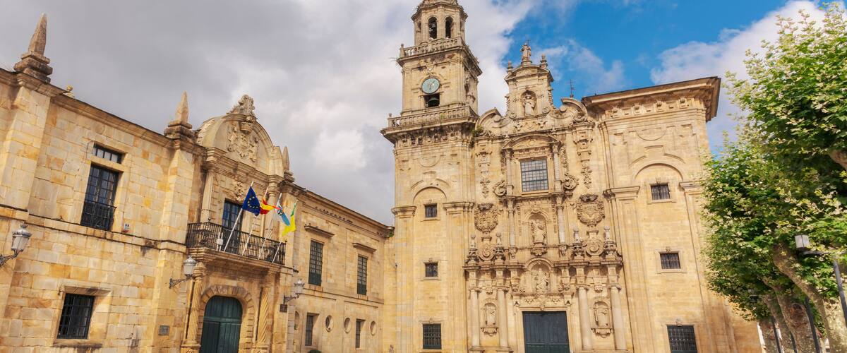 A historic building with ornate architecture, a clock tower, and flags.