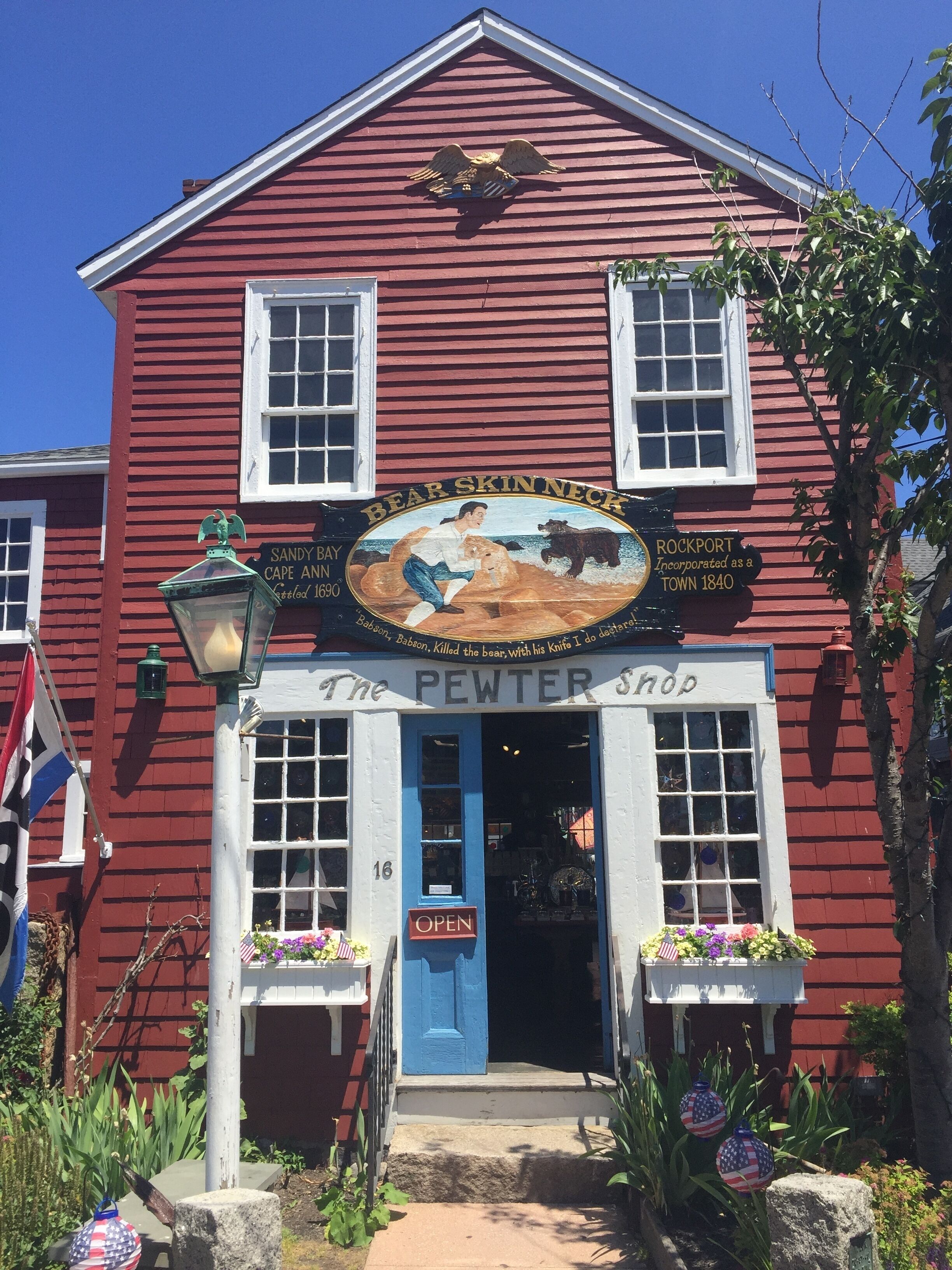 A red building with a sign reading "The Pewter Shop" and a bear skin neck emblem.