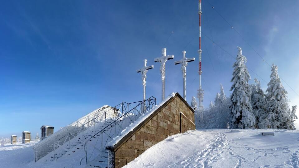 A snow-covered landscape with a wooden cabin, a metal staircase, and several tall communication towers.