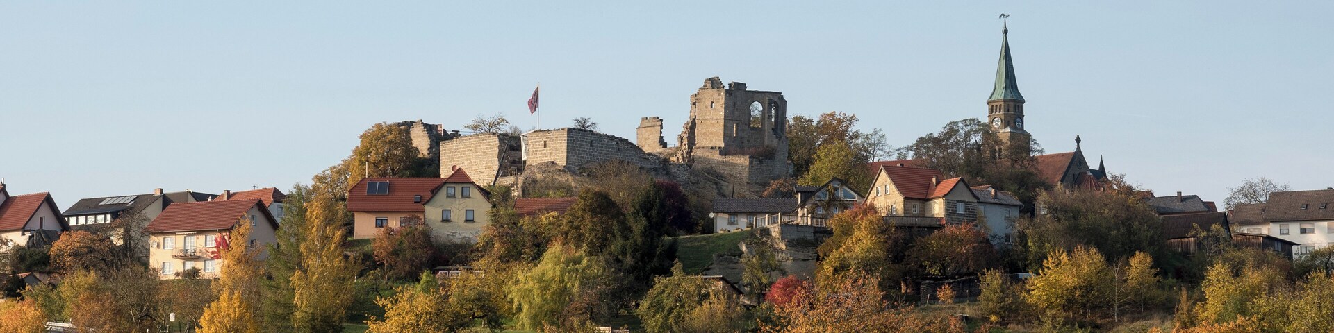 A historic town with a prominent church tower and castle ruins.