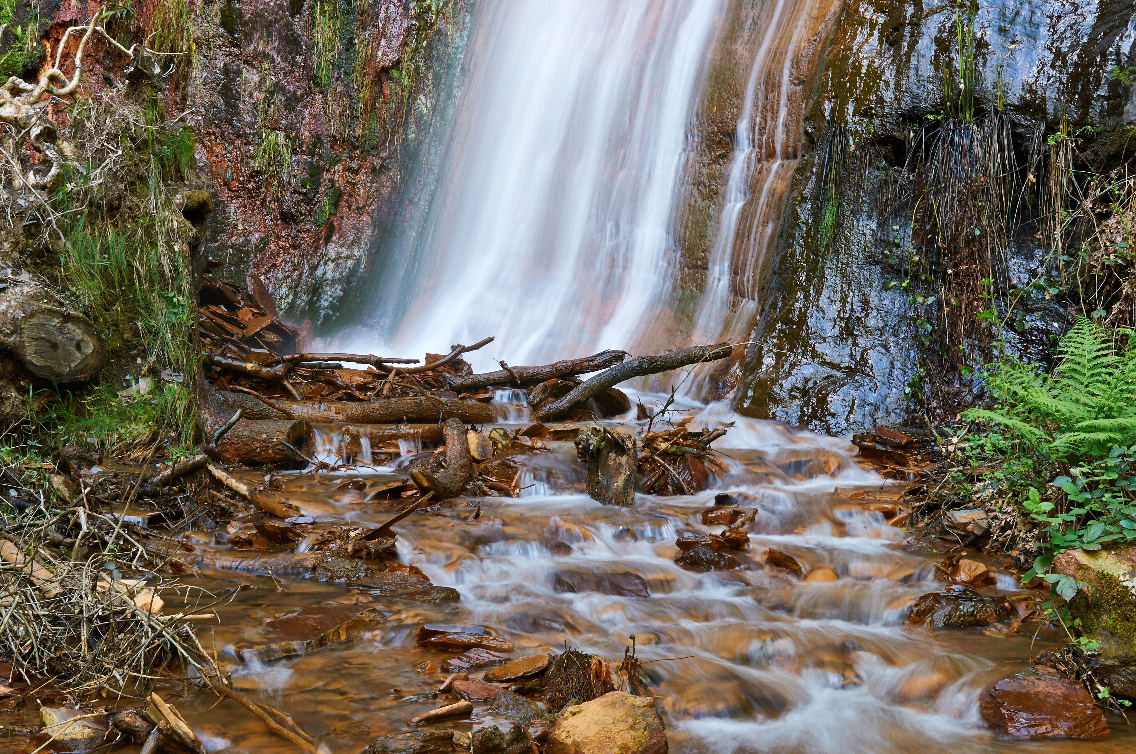 A waterfall flowing over rocks in a forested area.