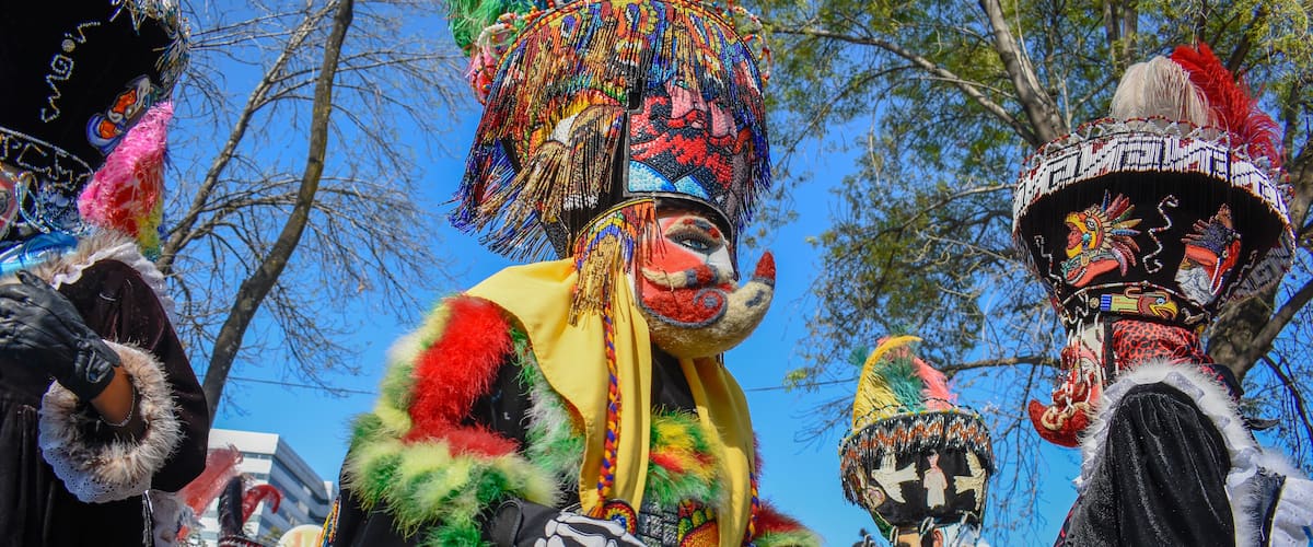 A person in a colorful, elaborate costume with a large, ornate headdress and a fur-trimmed outfit.
