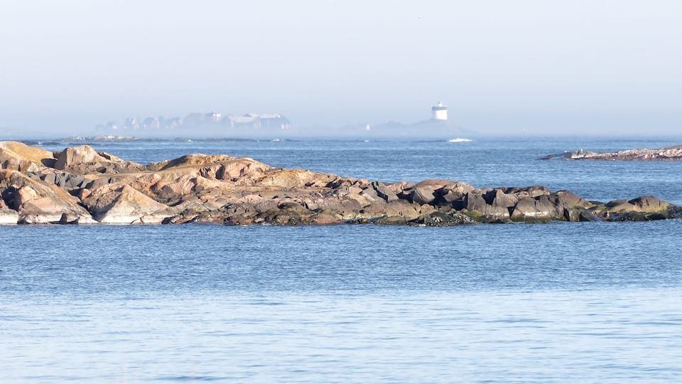 A rocky coastline with a lighthouse in the distance.