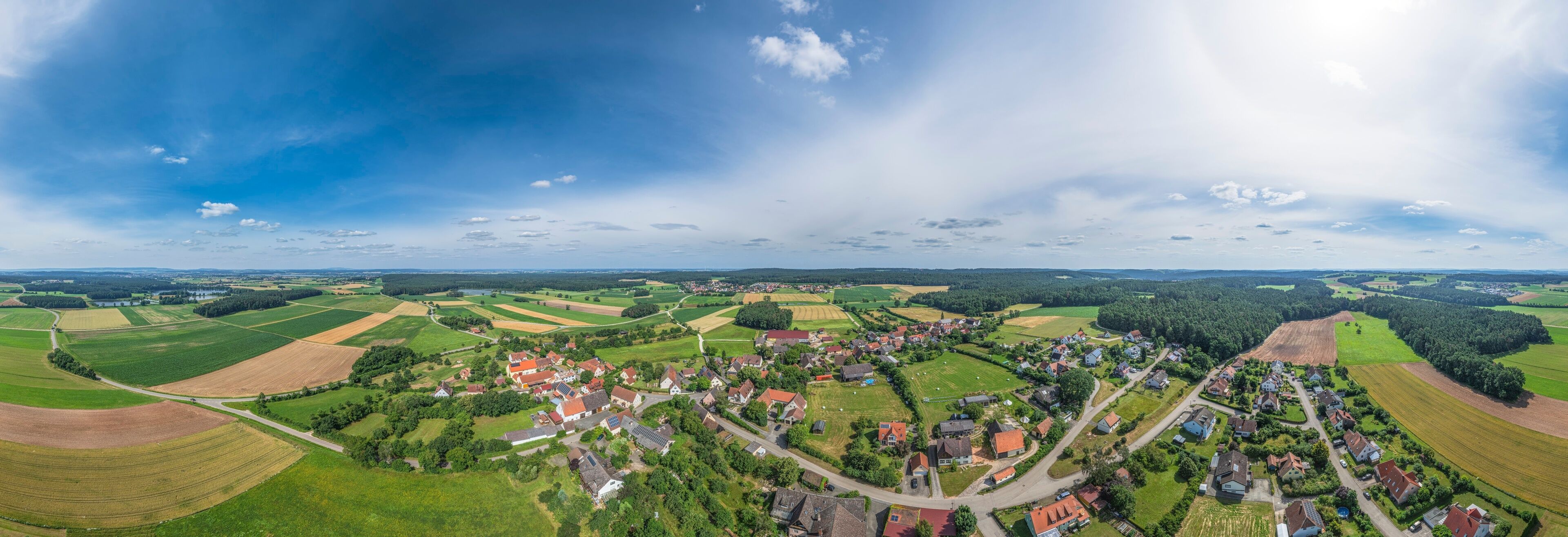 A rural landscape with fields, a village, and a large body of water.