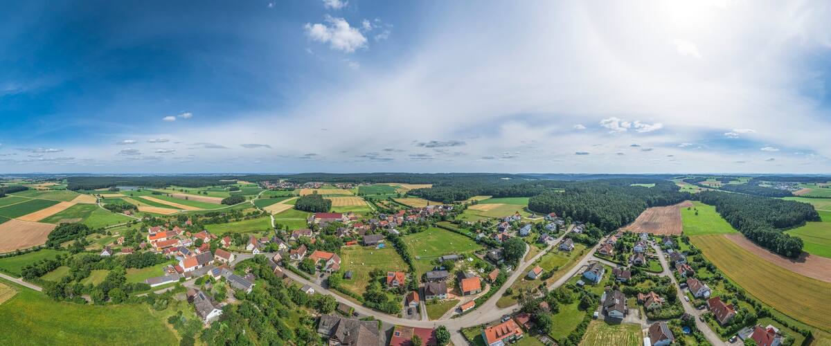 A rural landscape with fields, a village, and a large body of water.