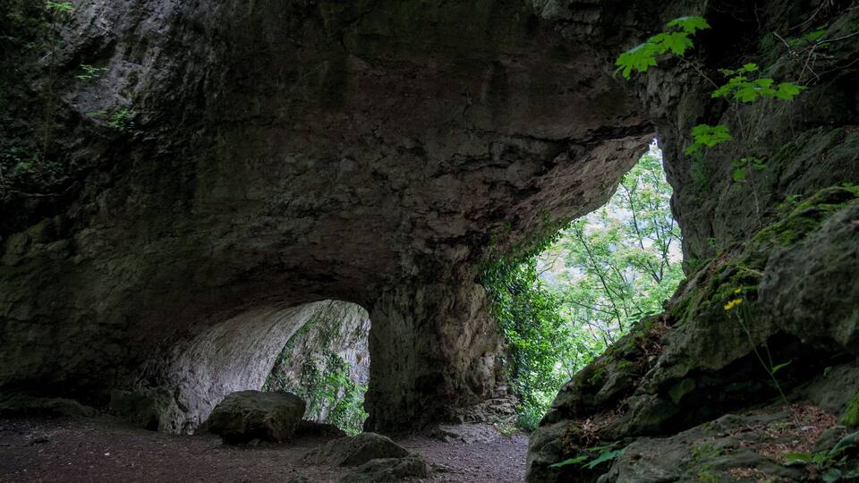 A natural rock arch formation with a dirt path leading through it.