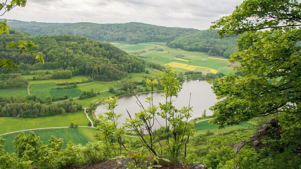 A valley with a lake, surrounded by green fields and hills.