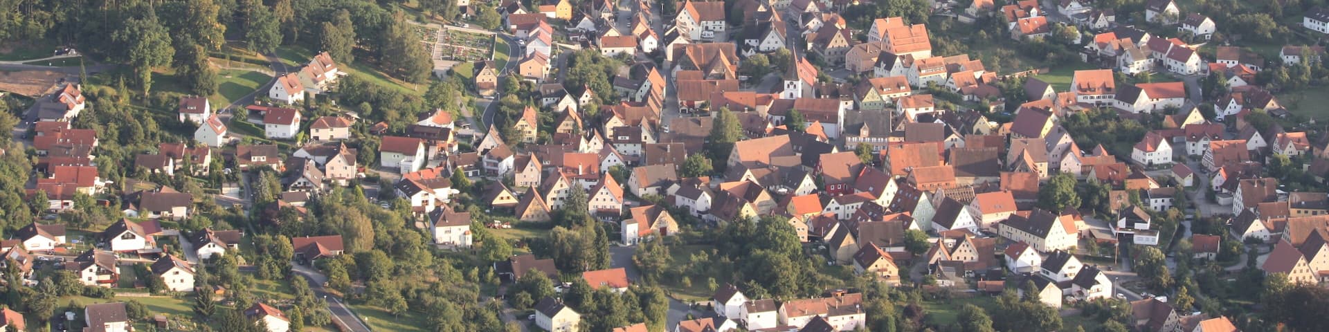 A town with red-roofed houses, a lake, and a church.