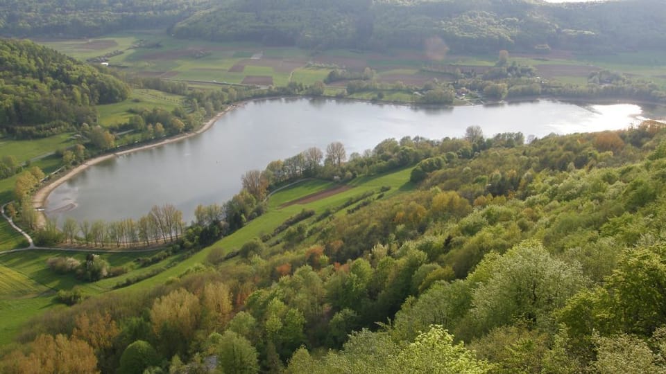 A lake surrounded by rolling hills and dense forests.
