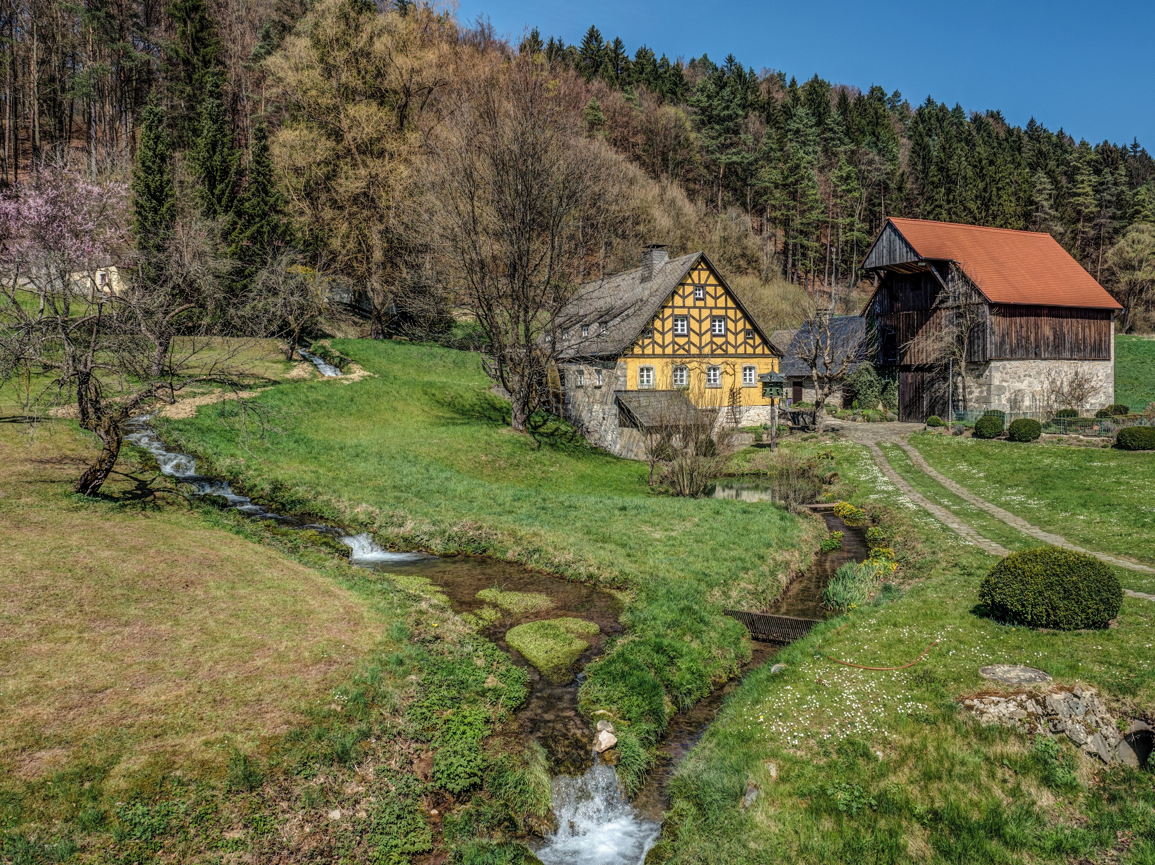 A traditional half-timbered house with a red-roof barn in a rural setting.